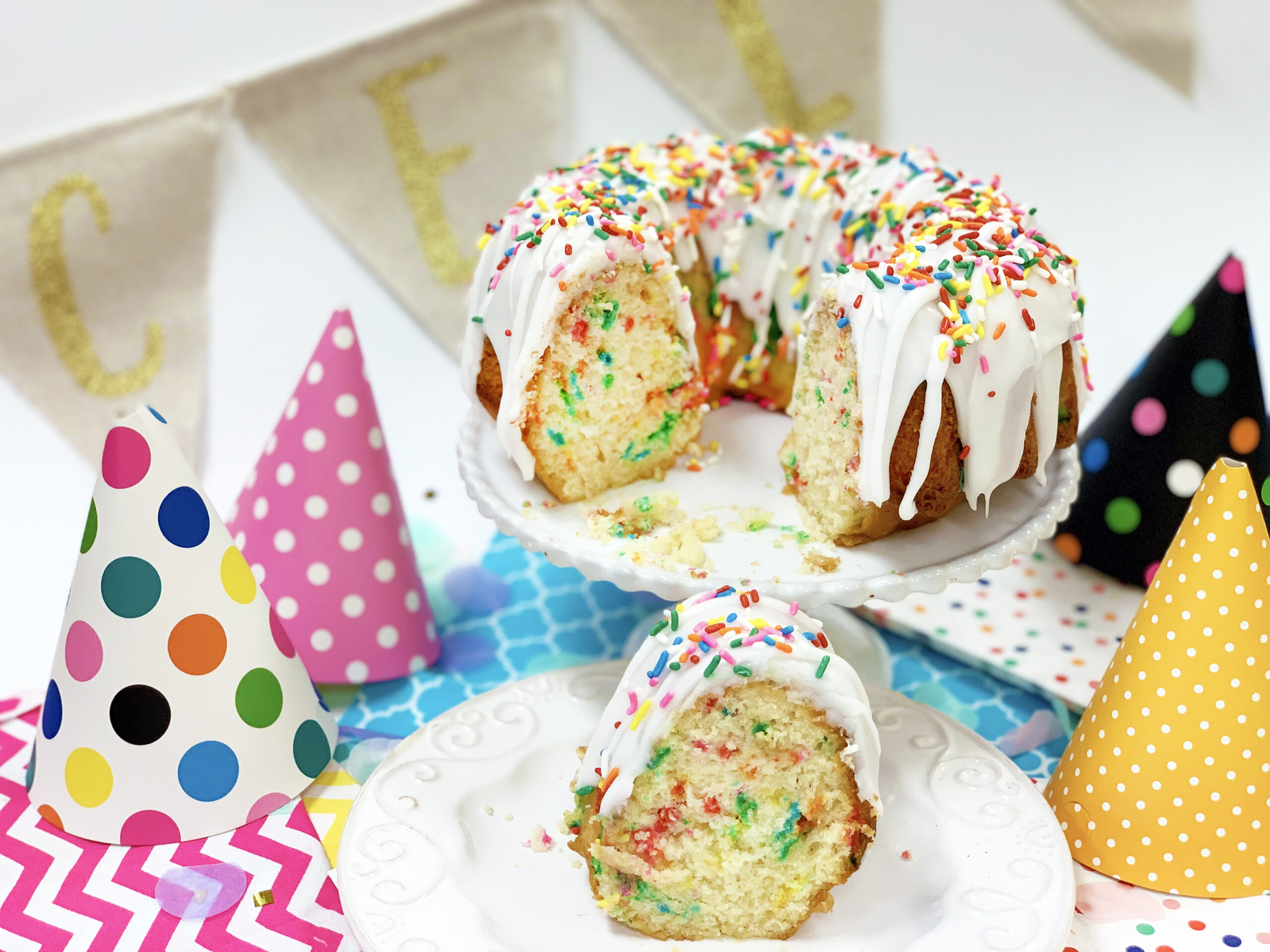 White iced bundt with sprinkles and party hats